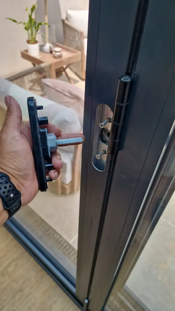 Locksmith repairing and refitting the handle and locking system on an aluminium bi-fold door.