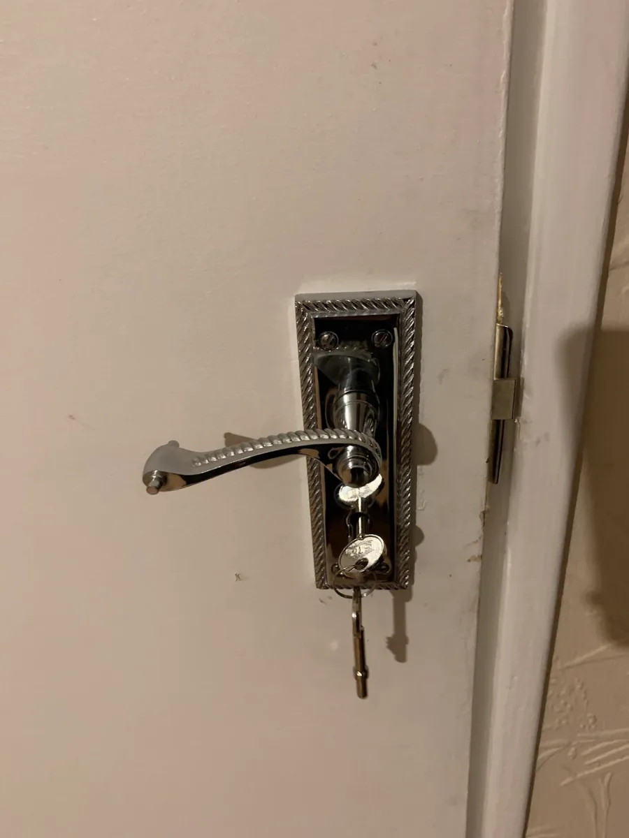 Chrome lever handle and lock newly fitted to a door, with keys in the cylinder
